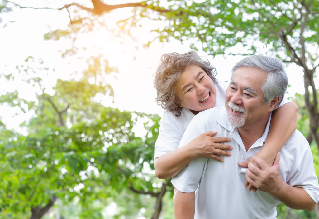 Senior woman piggy back senior man with love and happiness in park