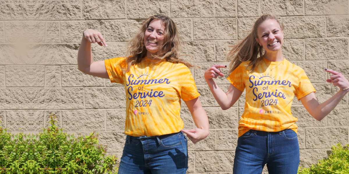 A couple of women who work at Life 97.3 wearing their bright yellow Summer of Service T-shirts and making fun poses